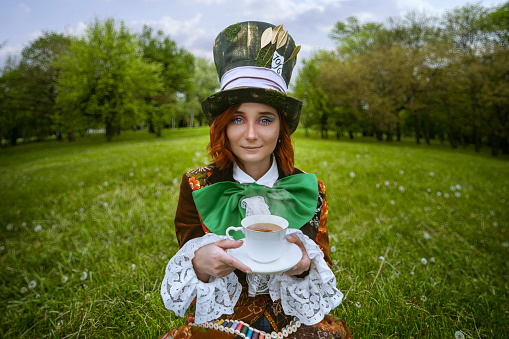 Beautiful woman as mad hatter with hats in nature