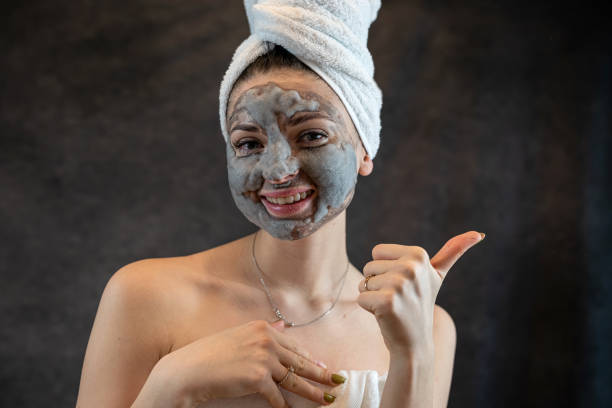 istock Female face with cosmetics cleansing gray bubble mask on dblack background 1490947570
