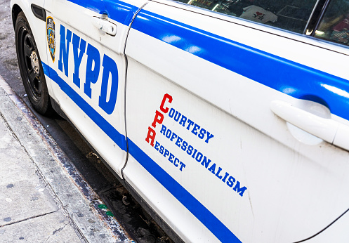New York City, USA - The side of a NYPD police car parked on a street in Manhattan, with the acronym CPR spelled out as 'Courtesy, Professionalism, Respect'.