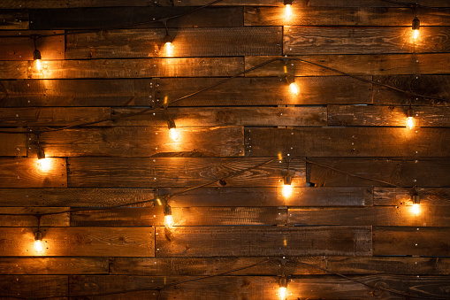 Edison lights illuminate a wooden plank backdrop for a rustic look at a wedding.