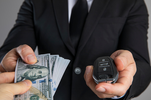 Businessman is holding a car key. A concept for buying/renting a car