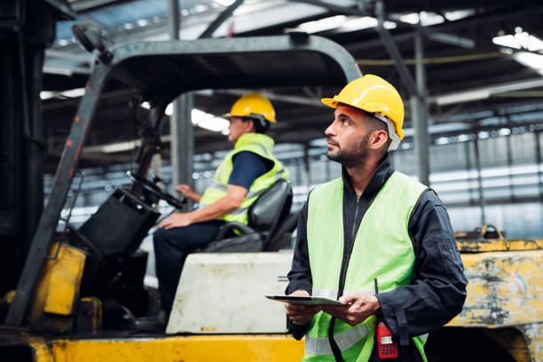 istock Engineer are working in the factory. Mechanical technicians are maintaining the engine. Worker with a forklift in a warehouse. 1490956480