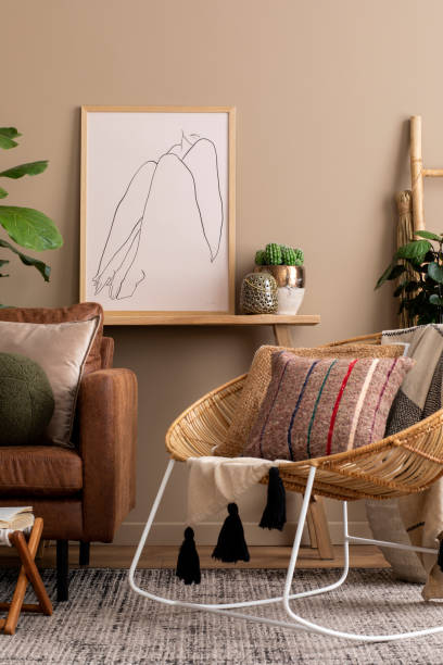 istock Creative composition of living room interior with mock up poster frame, brown sofa, braided armchair, colorful pillows, plants in flowerpots, wooden bench and personal accessories. Home decor Template 1490957385