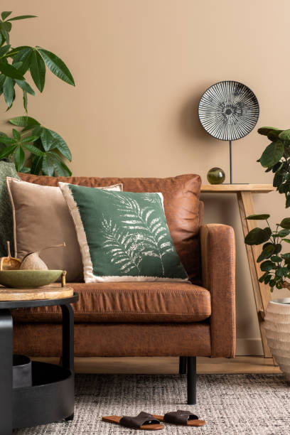 istock Interior design of living room interior with brown sofa, colorful pillows, patterned baskets, round coffee table, slippers, vase with eucalyptus and personal accessories. Home decor. Template. 1490957600