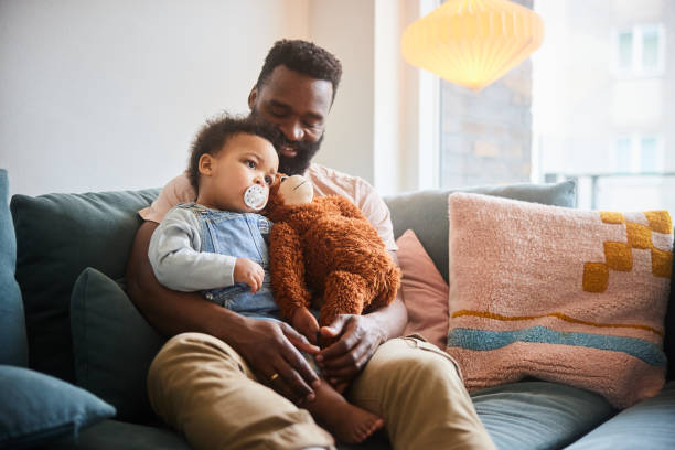 istock Dad sitting with baby boy and a stuffed monkey on their sofa 1490963060
