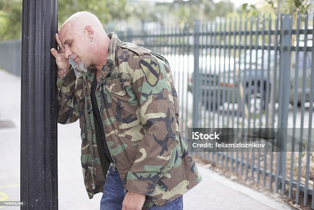 Tired Army Veteran Image of a tired army veteran leaning on the pole Adult Stock Photo