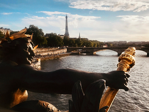 Nymphs of the Seine gilded statue on the Alexander III Bridge with the Eiffel Tower in the background in Paris