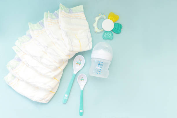 istock Baby's stuff with copy space. diapers with bottle for milk and spoons on blue background. Newborn, infant, baby shower gifts, healthcare concept 1490967743