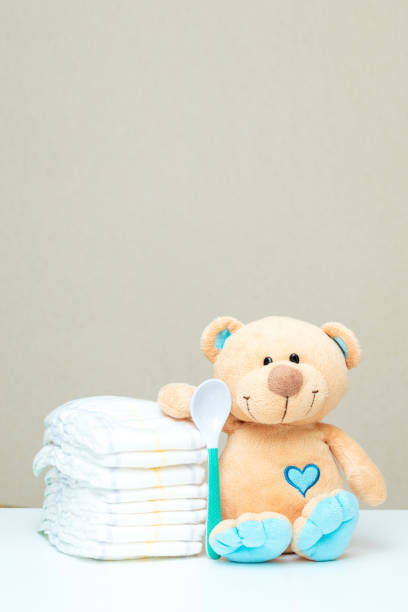istock Stack of diapers with toy teddy bear with spoon on table. set for baby shower with copy space 1490967761