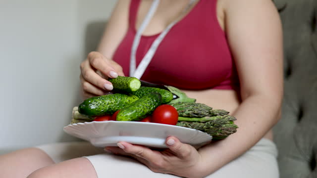 woman with measure tape on wrist and vegetables in plate in kitchen