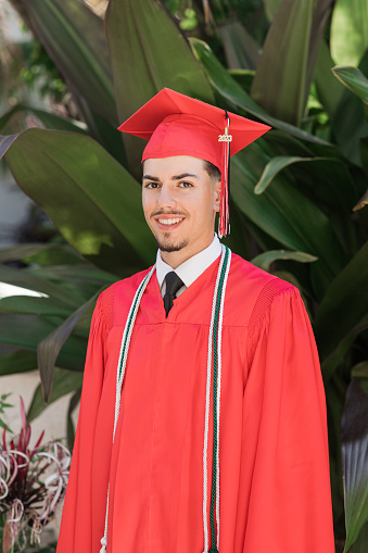 2023 High-School Senior Young Man in a Red Graduation Cap & Gown With Three Honors Tassels, A Well-Dressed 18-Year-Old Cuban-American with Brown Hair & Brown Eyes Looking Fresh & Sharp in a Suit & Tie in a Classy Location in Palm Beach, Florida