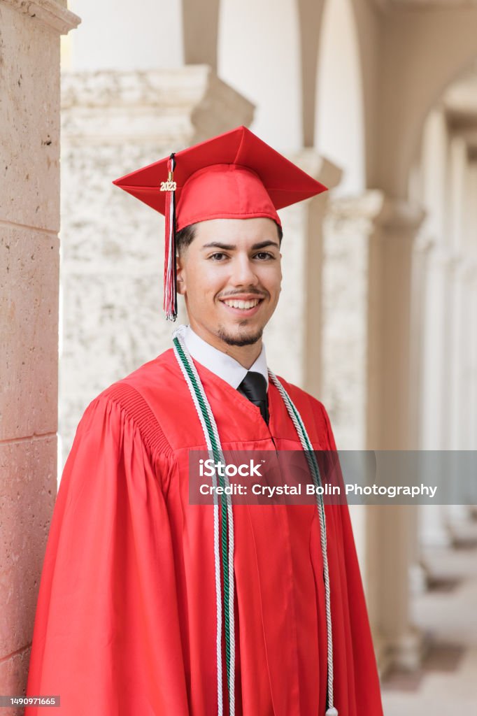 A 2023 High-School Senior Young Man in a Red Graduation Cap & Gown with Three Honors Tassels, A Well-Dressed 18-Year-Old Cuban-American with Brown Hair & Brown Eyes Looking Fresh & Sharp in a Suit & Tie in a Classy Location in Palm Beach, Florida A 2023 High-School Senior Young Man in a Red Graduation Cap & Gown With Three Honors Tassels, A Well-Dressed 18-Year-Old Cuban-American with Brown Hair & Brown Eyes Looking Fresh & Sharp in a Suit & Tie in a Classy Location in Palm Beach, Florida Graduation Stock Photo