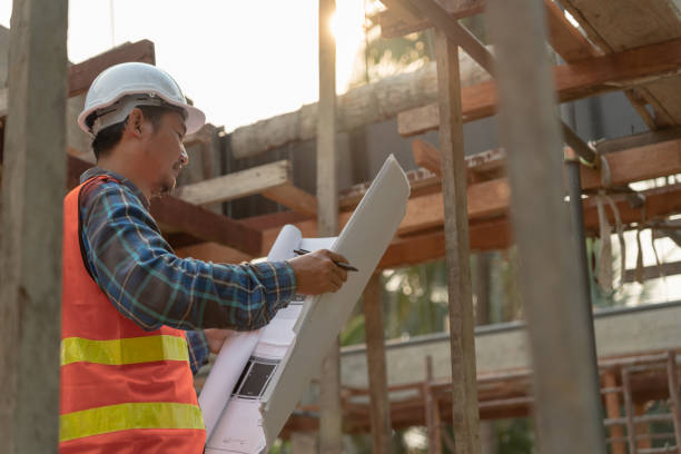 検査官またはエンジニアは、青写真を使用して建設および品質保証の新しい家を検査しています。エンジニア、建築家、またはコンタクタは、住宅所有者に引き渡す前に家を建てるために働� - house quality control examining construction ストックフォトと画像
