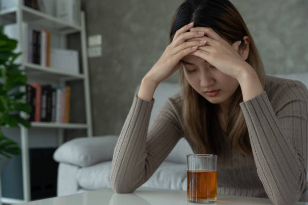 istock Depressed young Asian woman addicted feeling bad drinking whiskey alone at home, stressed frustrated lonely drinking alcohol suffers from problematic liquor, alcoholism, life and family problems 1490974405