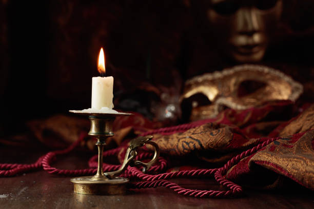istock Burning candle in an old brass candlestick and carnival masks. 1490975302