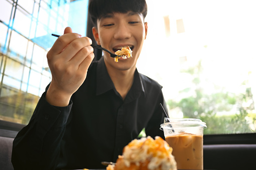 Enjoy eating with Young Asian man eating croissant, Selective focus on fork.