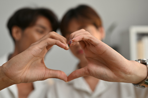 Selective focus on Asian teenage gay couple hands making heart shape, Support marriage equality for LGBT people.