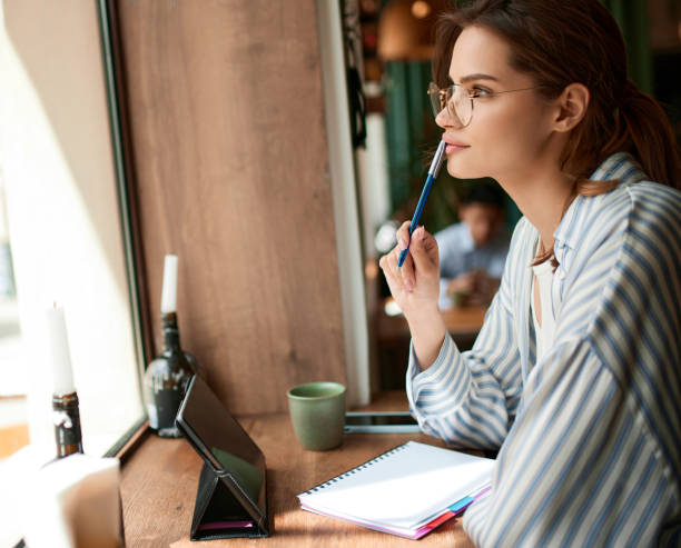 istock Beautiful young female freelancer using tablet while sitting at a table in cafe. Happy smiling girl working online or studying. Freelance work, business people 1490980446