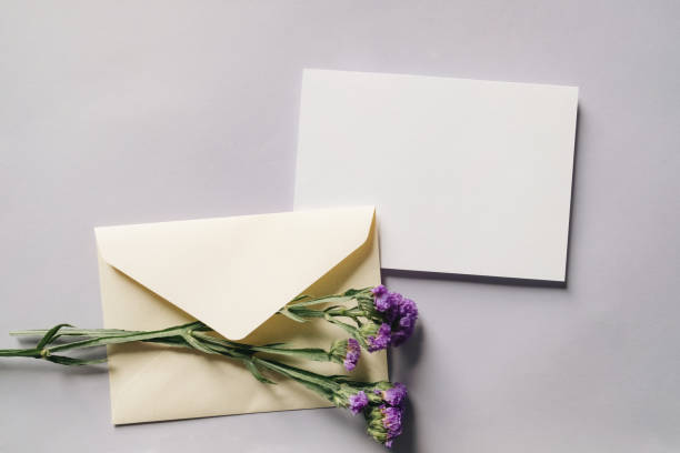 istock White blank greeting or invitation card and envelope with white flowers decoration on gray background. Mock up presentation. 1490983291