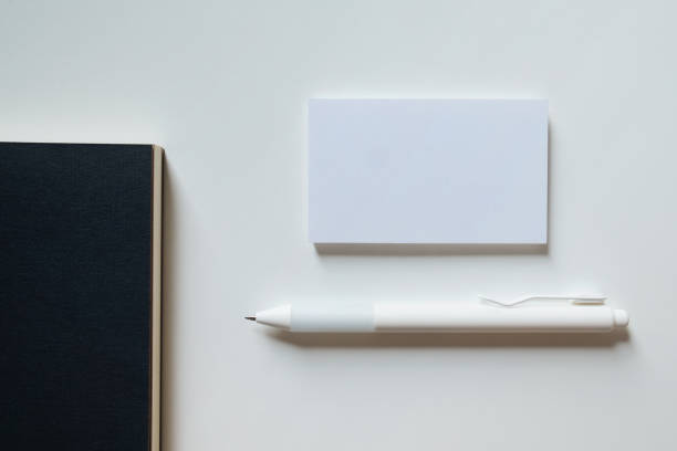 istock White blank business card mockup, black notebook and pen on white background. Mock up presentation. 1490983421