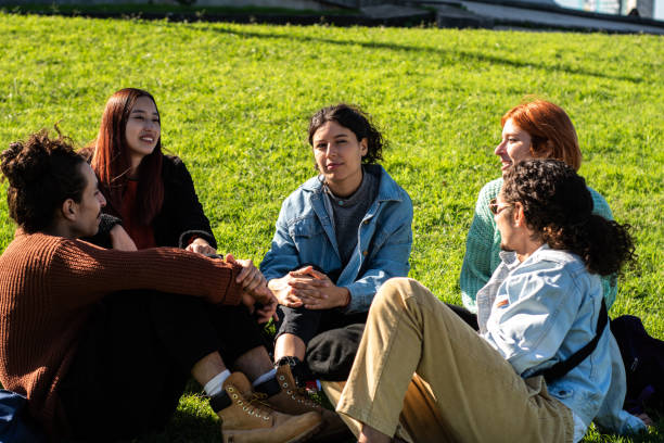 istock Young friends talking sitting on grass at public park 1490985671