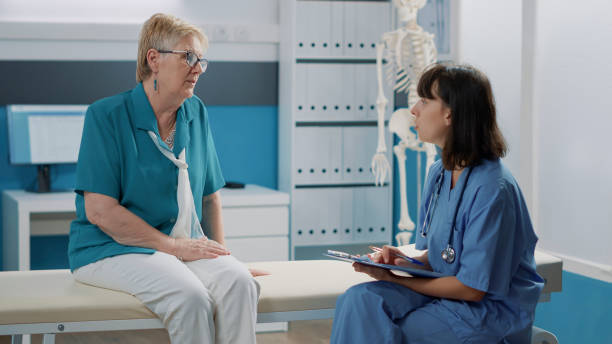istock Female nurse taking notes on files after examination with old patient 1490986722