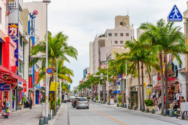This photo was shot at Okinawa's downtown/tourist attraction, Kokusai Street in Naha, Okinawa on January 4, 2023. There are pedestrians and cars in this photo.