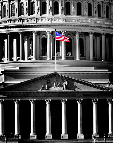 United State Capitol Building for congress with american flag flowing in breeze and columns in background