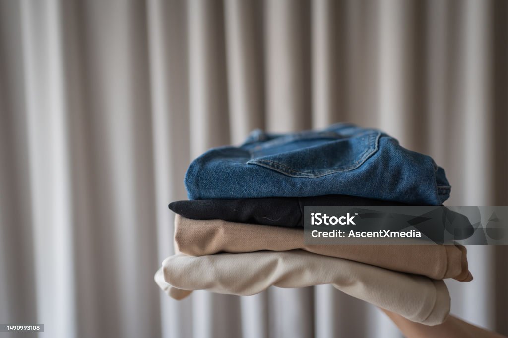 Stack of clothing and curtain Hand holds stack of clothing Backgrounds Stock Photo
