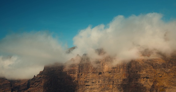 White clouds over mountain peaks. Los Gigantes cliffs on ocean coastline at sunny day. Tenerife Canary Islands.