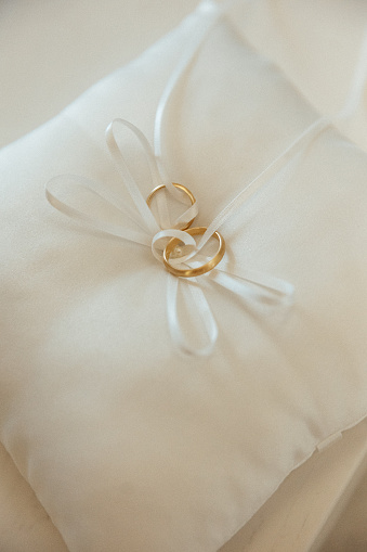 Two golden wedding rings and pearls on white background.\tWedding banner