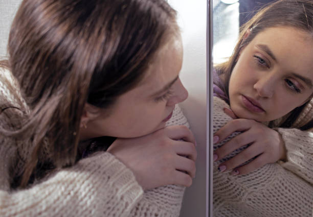 istock sad girl in depression looks at her reflection in the mirror 1491005327