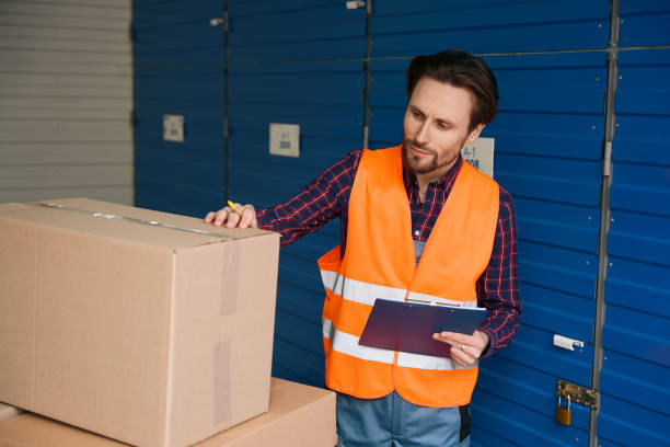 istock Waist-up of guy in work clothes with boxes into warehouse with self storage unit 1491006617