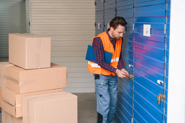 istock Young man in work clothes with big cardboard boxes into warehouse 1491006660