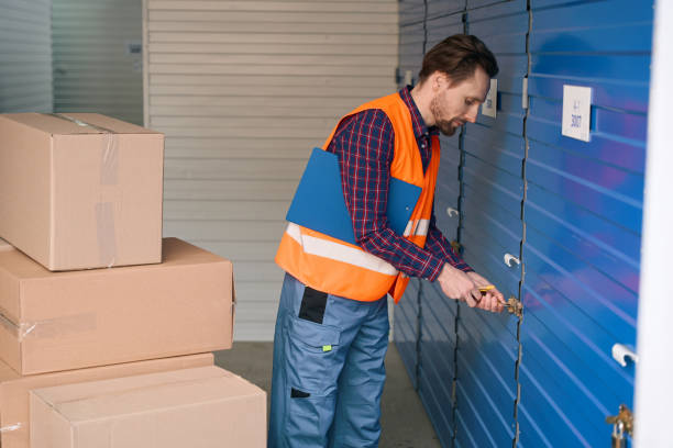 istock Side view of young guy in work clothes with big cardboard boxes into warehouse 1491006745