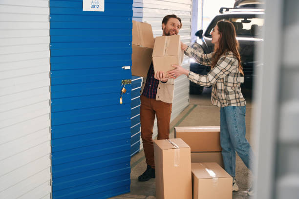 istock Young couple with big cardboard boxes into warehouse with self storage unit 1491007302