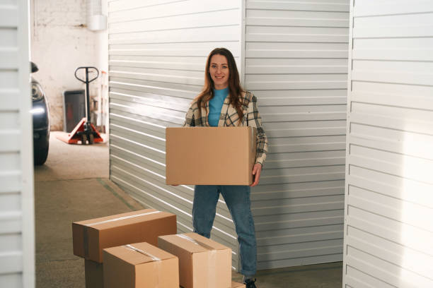 istock Young lady with big cardboard boxes into warehouse with self storage unit 1491007332