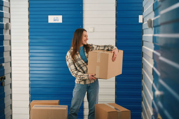 istock Young lady with big cardboard boxes into warehouse with self storage unit 1491007355