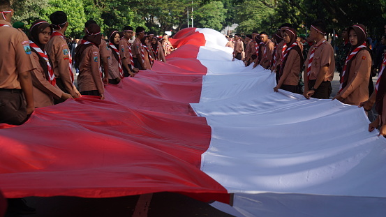 Kediri, East Java, Indonesia - May 12th, 2023 : Indonesian scouts unfurl the national flag at the Kirab Kebangsaan (national carnival)
