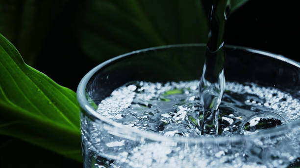 el agua mineral carbonatada se vierte en un vaso. - water flowing water pouring ice fotografías e imágenes de stock