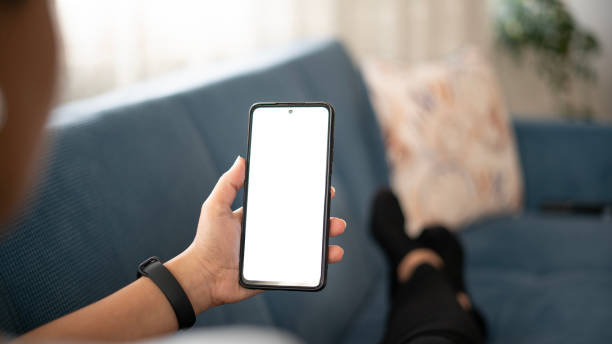 istock Woman using phone with white screen while lying on sofa at home , mock up screen 1491020574
