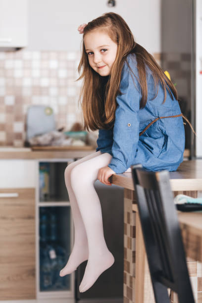 istock Happy little girl sitting on kitchen table at home 1491023195