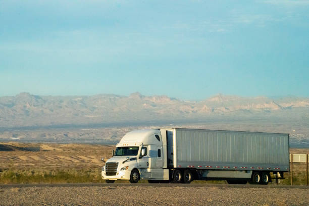 istock A white semi truck rumbled through the Nevada Desert, its powerful engine cutting through the vast expanse. Against the backdrop of majestic mountains, the setting sun painted the sky in fiery hues. 1491023979