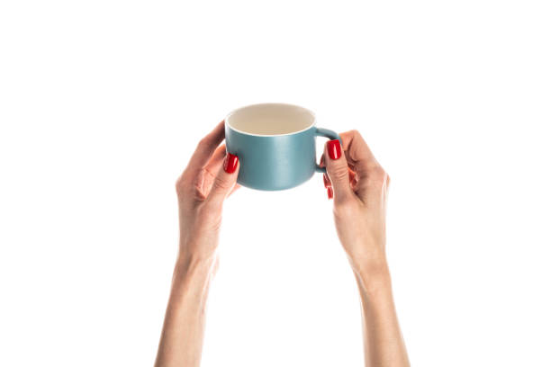 istock Female hands hold a white ceramic cup on white background. Female hands with fresh red manicure. Isolated on white background. 1491025201