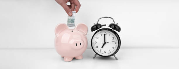 istock Womans hand put dollar bancnote into a piggy bank with alarm clock 1491027114
