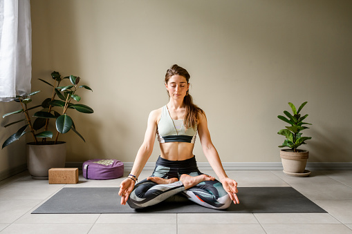 Professional woman practicing yoga at home: Lotus, Padmasana