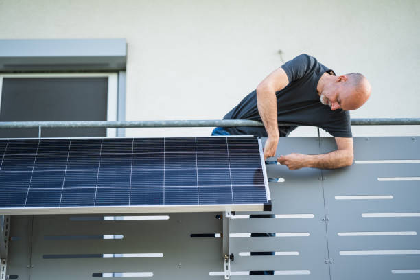 man mounting solar panel on balcony stock photo