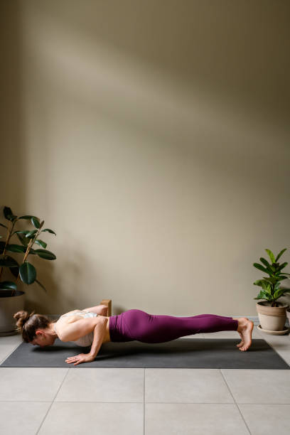 Professional woman practicing yoga at home: Low Push-up, Chaturanga Dandasana stock photo