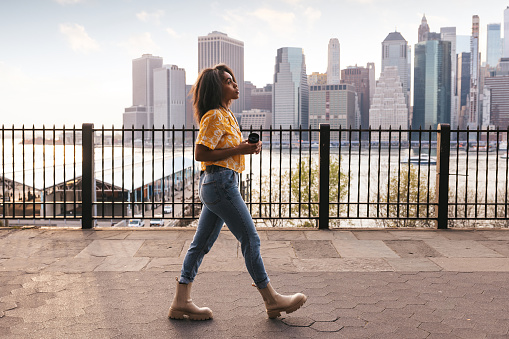 Woman walks in Brooklyn Heights with New York cityscape on the background