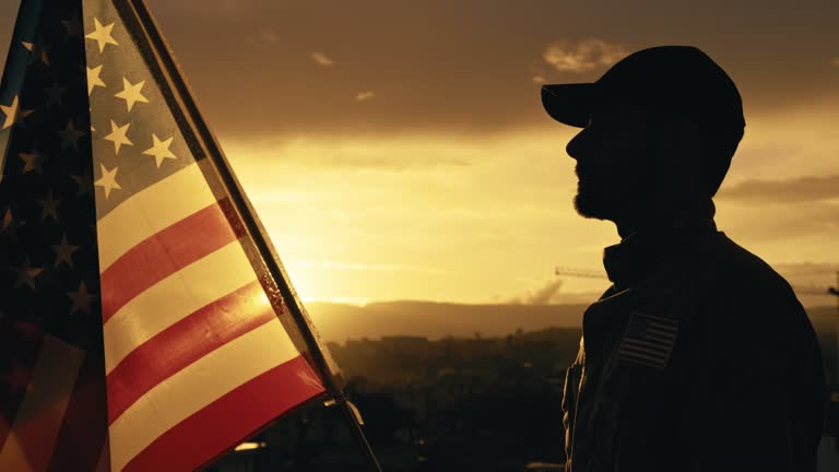 Silhouette of Military Salute of soldier for memorial day against flag at sunset